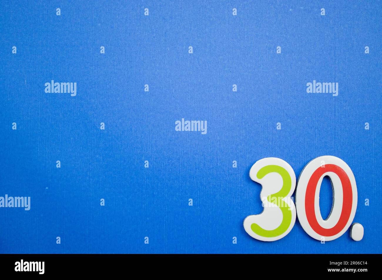 Il numero 30, posto sul bordo dello sfondo blu, fotografato dall'alto, di colore verde e rosso. Foto Stock