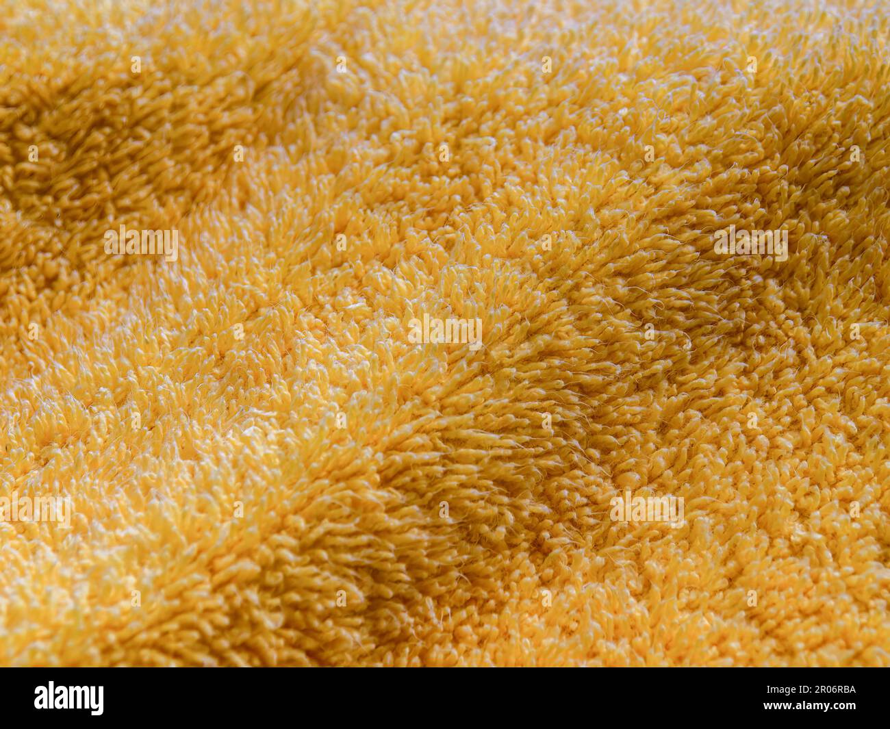 Macro fotografia di un asciugamano di cotone giallo illuminato dal sole del mattino. Foto Stock