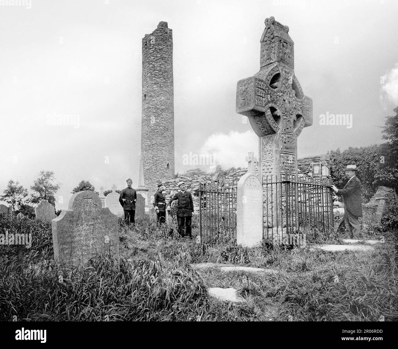 Una vista di fine 19th ° secolo dei visitatori che ammirano la Croce Ovest a Monasterboice un insediamento monastico paleocristiano nella Contea di Louth in Irlanda, a nord di Drogheda. Le tre croci alte sul sito monastico risalgono al 10th° secolo e fanno parte del gruppo scritturale, che mostra scene bibliche. La torre rotonda è alta circa 28 metri, probabilmente fu costruita poco dopo il 968 e danneggiata in un incendio nel 1098. Foto Stock