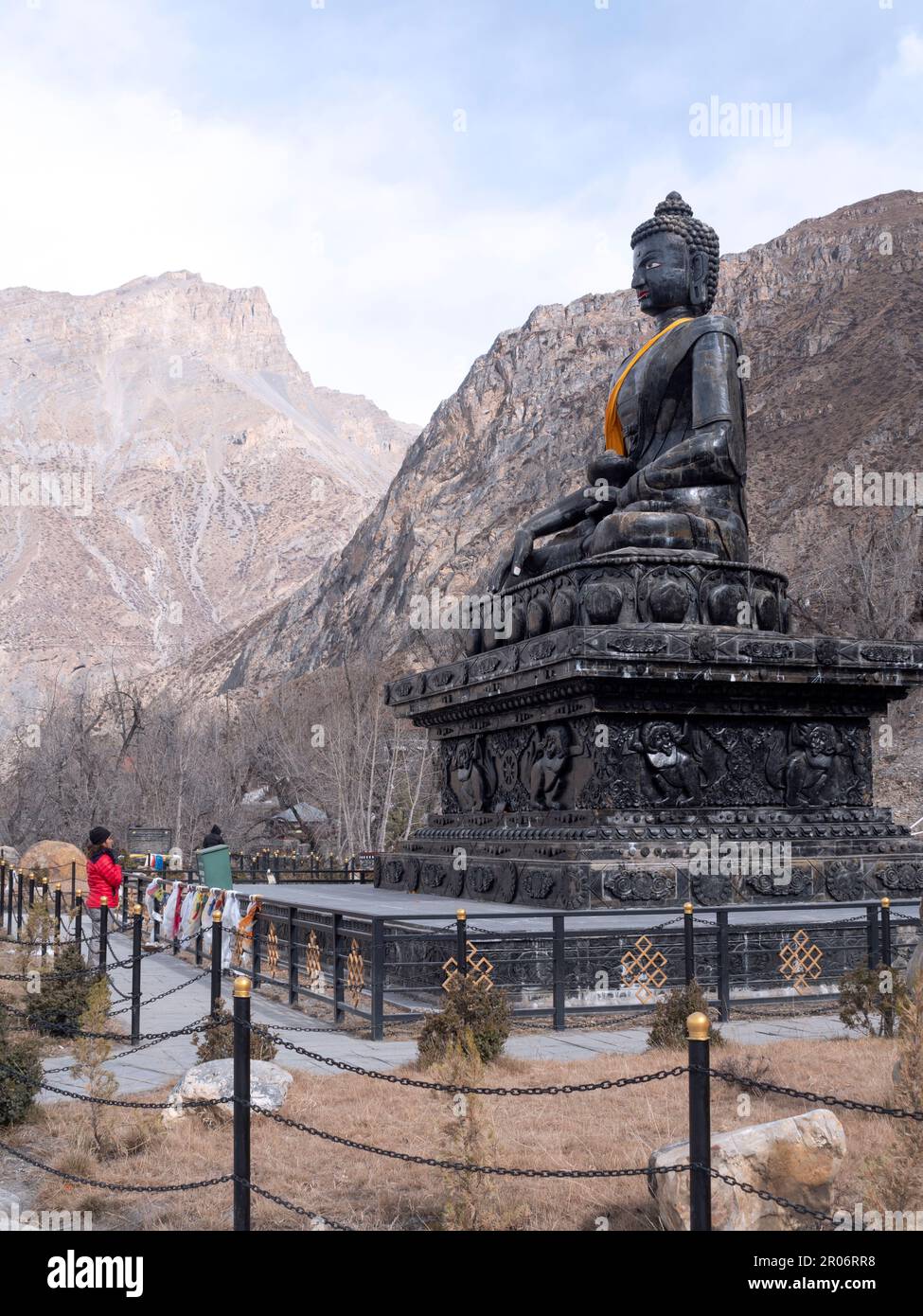Saccopelatore femmina a Muktinath, Nepal, in preghiera in Namaste mudra di enorme Buddha di pietra. Foto Stock