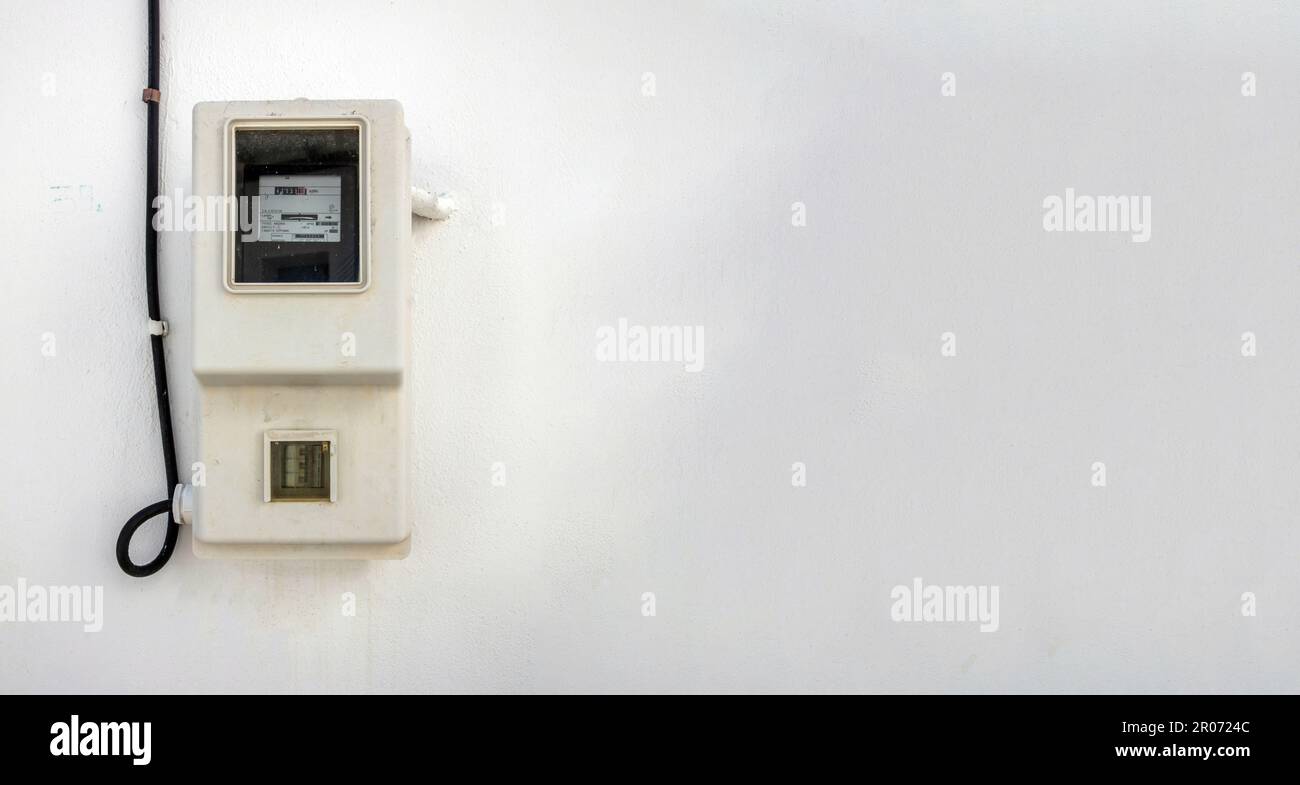 Vecchio dispositivo di contatore elettrico all'aperto su fondo vuoto muro imbiancato, isola delle Cicladi, Grecia. Misura di kilowattora. Spazio di copia Foto Stock