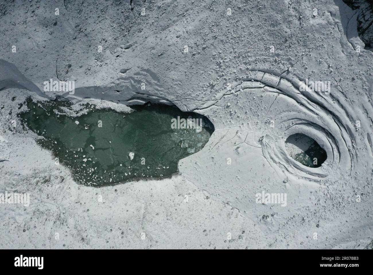 Vista aerea del ghiacciaio con acqua ghiacciata, crepacci circolari e orizzontali e neve - Alpe Italiana Foto Stock