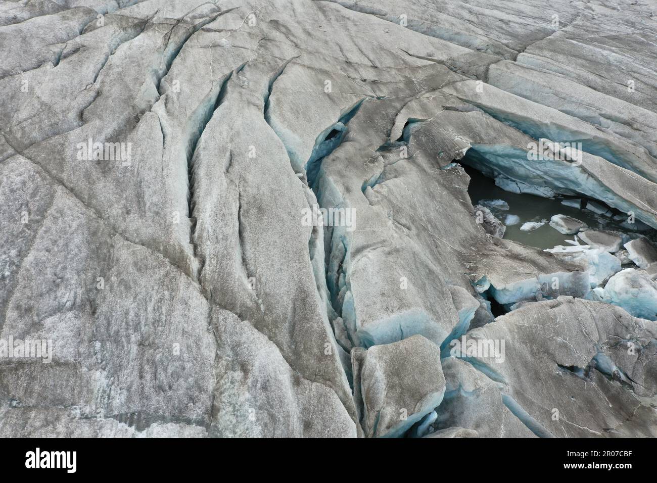 Vista aerea del ghiacciaio con acqua ghiacciata, crepacci circolari e orizzontali e neve - Alpe Italiana Foto Stock