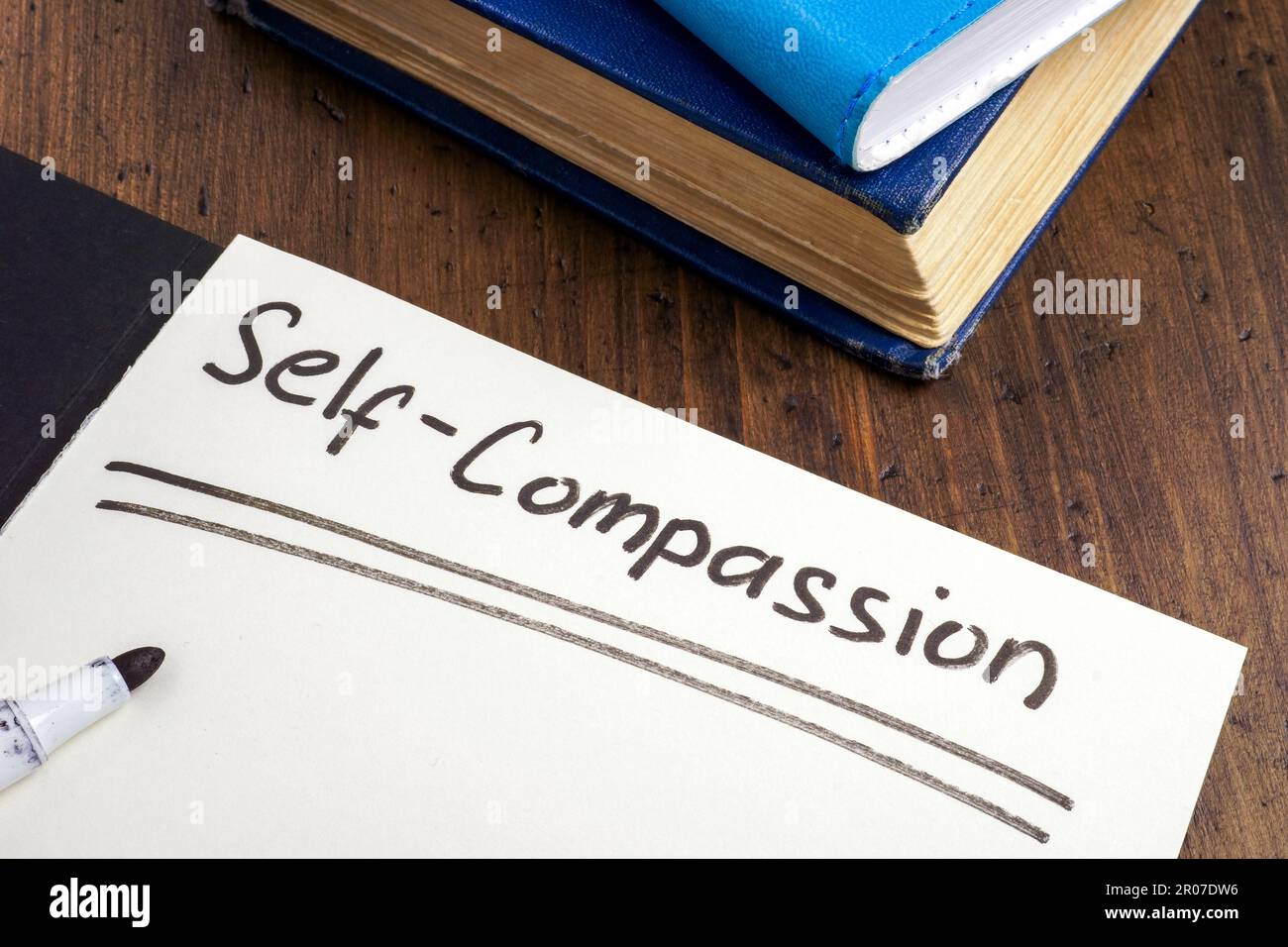 Aprire il blocco note con iscrizione auto-compassione e libro. Foto Stock