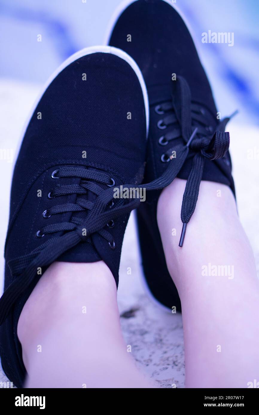 Una persona che indossa un paio di scarpe nere con un fulmine viola Foto Stock