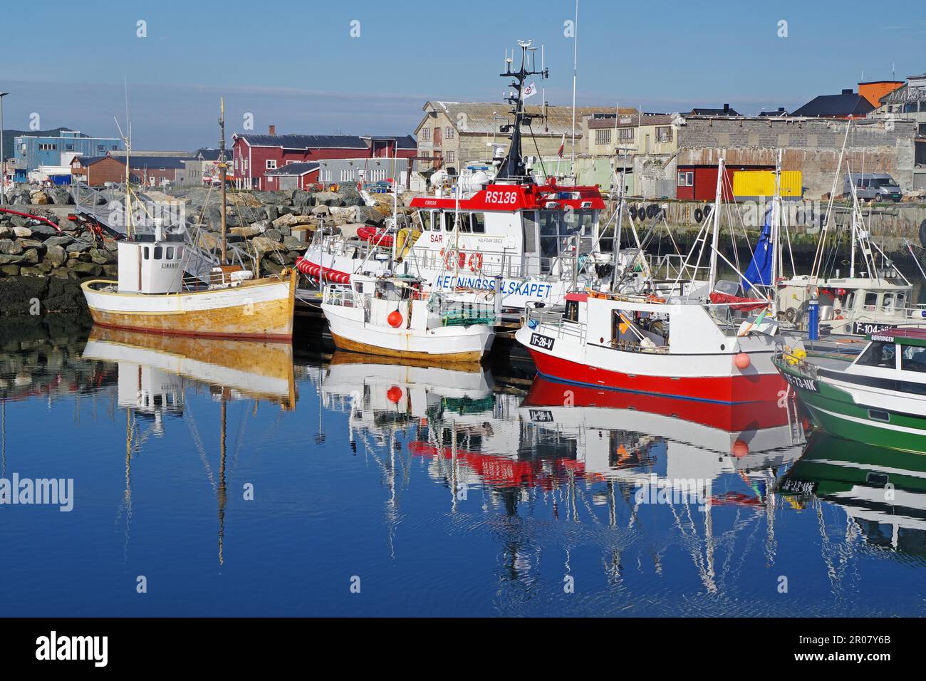 Barche da pesca riflesse nelle acque dolci di un bacino portuale, Cattedrale del Mare di ghiaccio, Vardoe, Penisola di Varanger, Finnmark, Artico, Norvegia Foto Stock