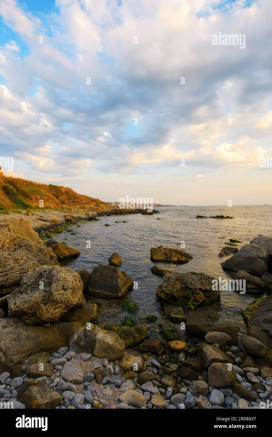 costa di ciottoli all'alba. splendida vista sul mare in una mattinata nuvolosa. relax e ricreazione al mare Foto Stock