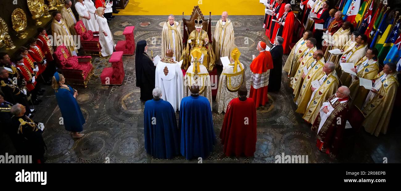 Re Carlo III, circondato da capi di fede seduti nella Cattedra di Sant'Edoardo, nota anche come Cattedra di incoronazione, indossando la Corona di Sant'Edoardo che tiene lo Sceptre del Sovrano con la colomba (nella sua mano sinistra) e lo Sceptre del Sovrano con la Croce (nella sua mano destra), Durante la sua cerimonia di incoronazione nell'Abbazia di Westminster, Londra. Data immagine: Sabato 6 maggio 2023. Foto Stock