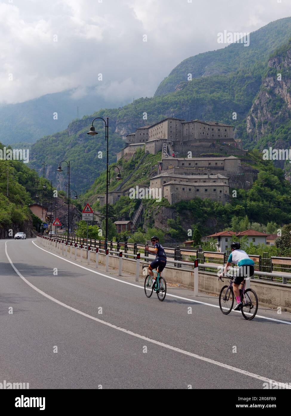 I ciclisti passano dal forte di Bard (forte di Bard) in Valle d'Aosta, NW Italia Foto Stock