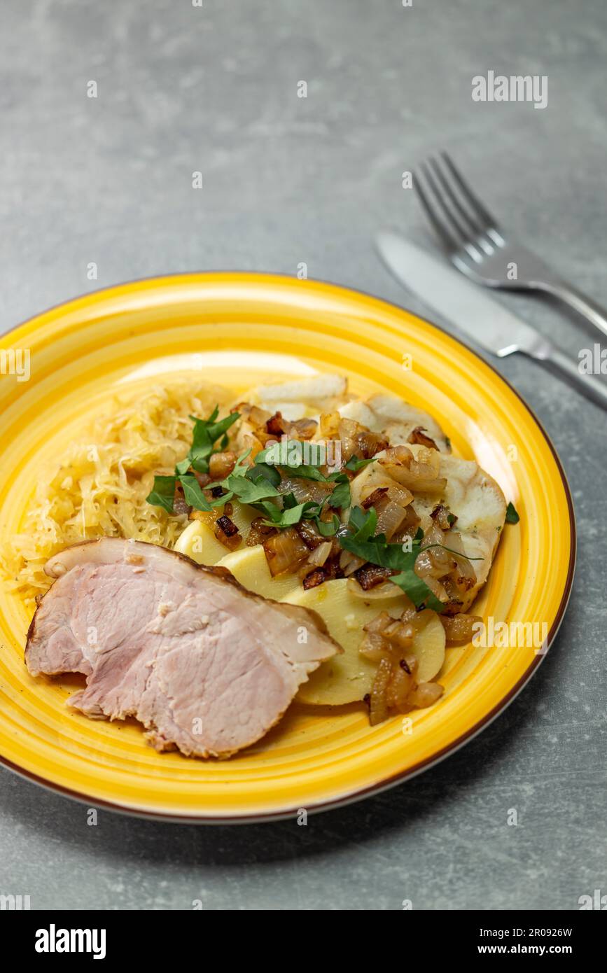 carne di maiale con gnocchi di patate e cavolo sottaceto servito con cipolla arrosto Foto Stock