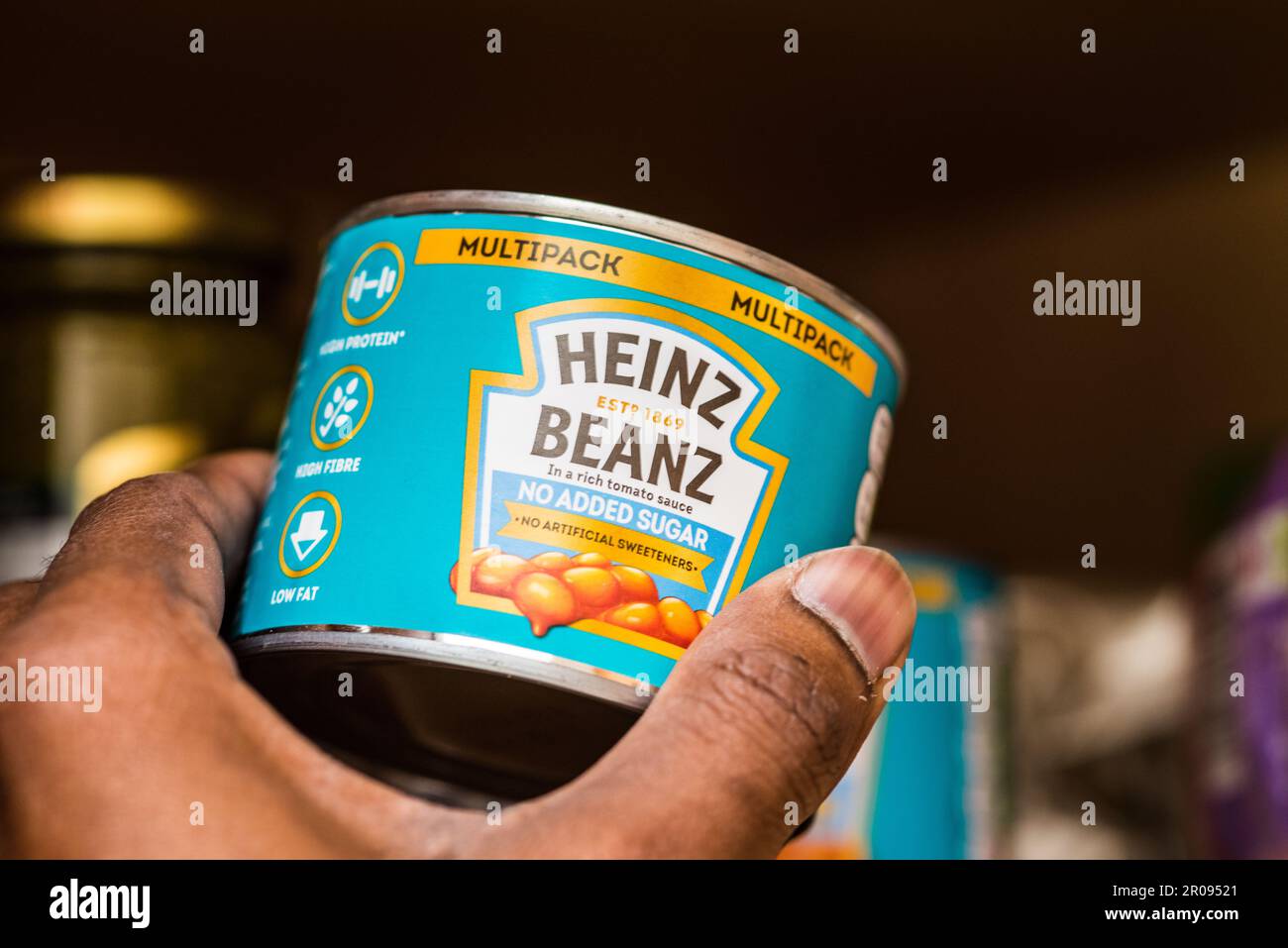Maschio adulto che raccoglie Heinz Beanz cibo in scatola da casa scaffale Foto Stock