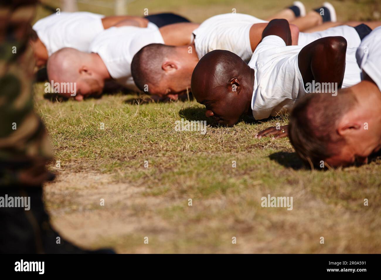 Spingiti al limite di bootcamp. un gruppo di uomini che fanno push-up in un bootcamp militare. Foto Stock