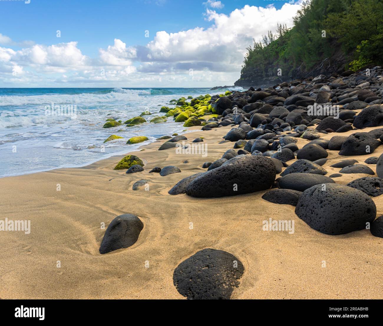 Lava Rocks e Golden Sand contro le scogliere di Na Pali a Hanakapiai Beach, Kauai, Hawaii, USA Foto Stock