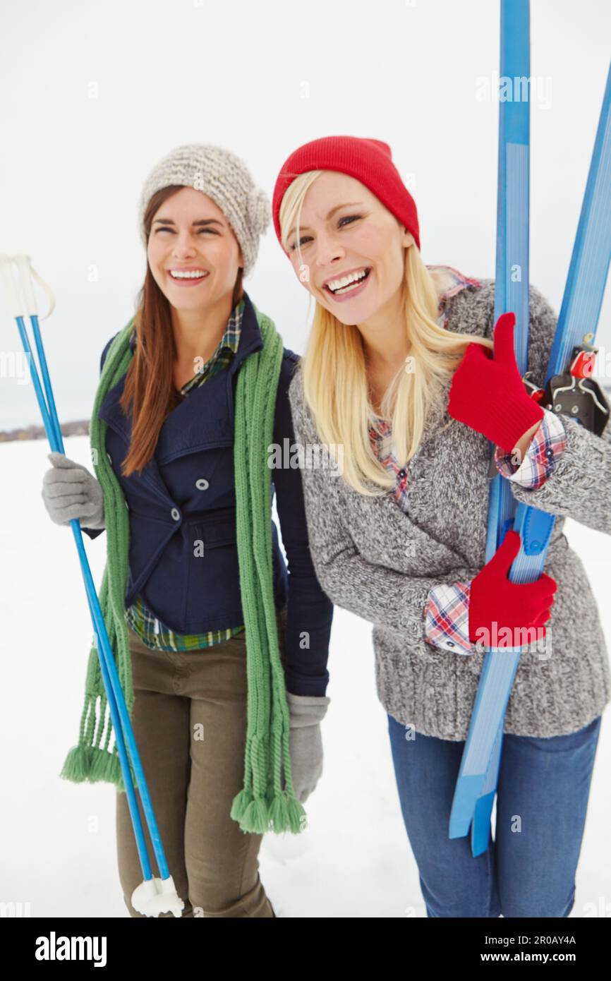 Una giornata fantastica per sciare con un amico. Scatto di tre quarti di lunghezza di due giovani donne che detengono l'attrezzatura da sci. Foto Stock