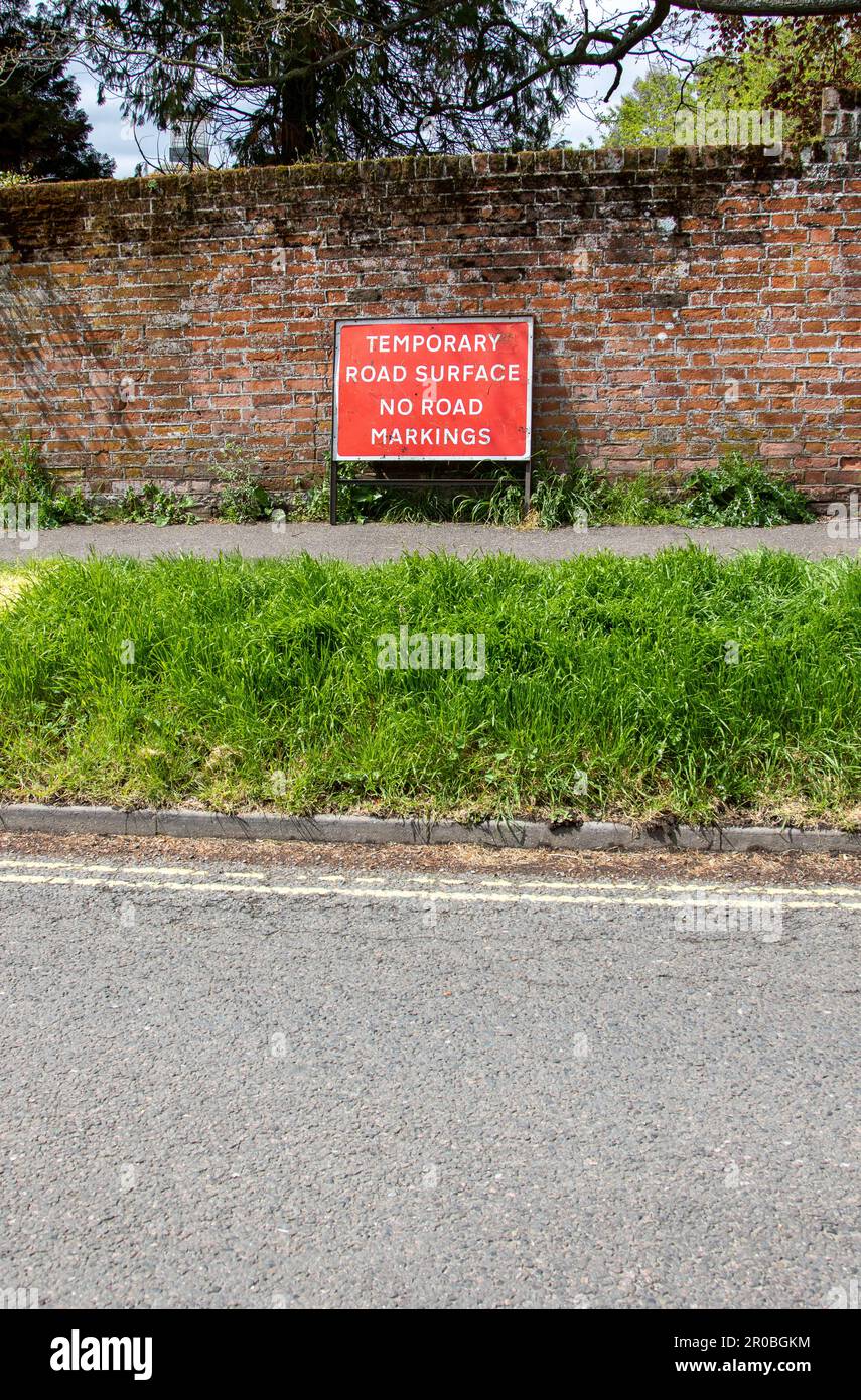 Un cartello stradale di segnalazione fuori luogo è stato appeso sul marciapiede da un muro nella piccola città di mercato di Suffolk di Framlingham Foto Stock