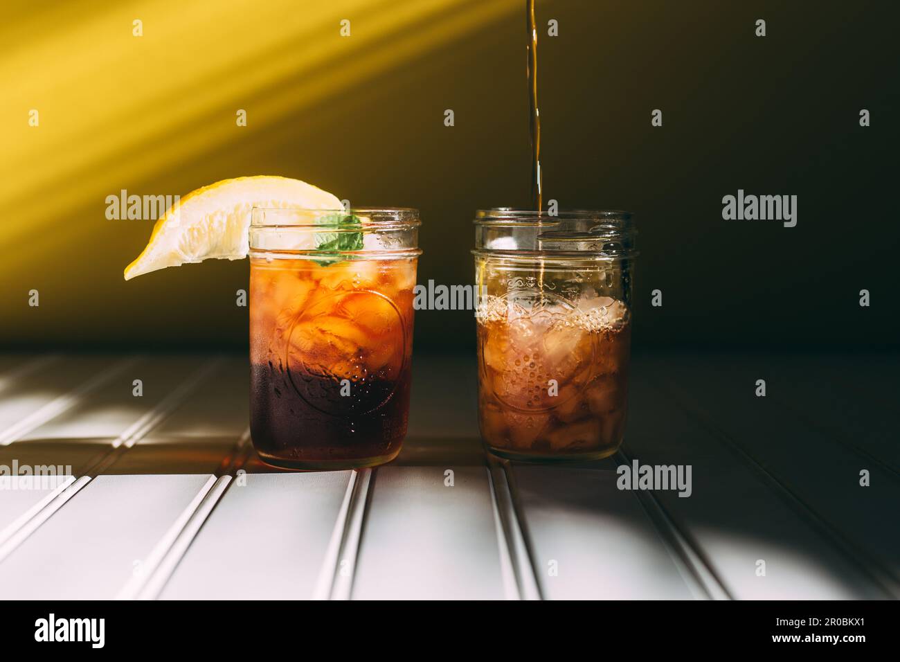 Versare il tè in una finestra luminosa con sfondo giallo Foto Stock