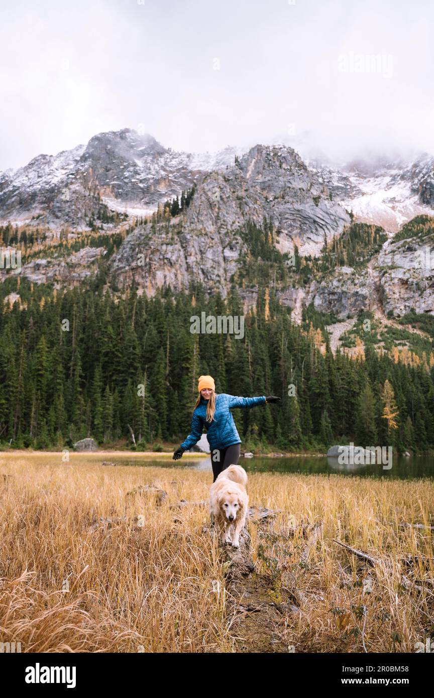 Ragazza con il suo cane escursioni in montagna con larici caduta Foto Stock