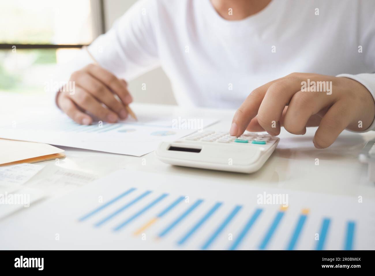 Uomo d'affari che utilizza una calcolatrice che analizza il grafico degli investimenti sul Foto Stock