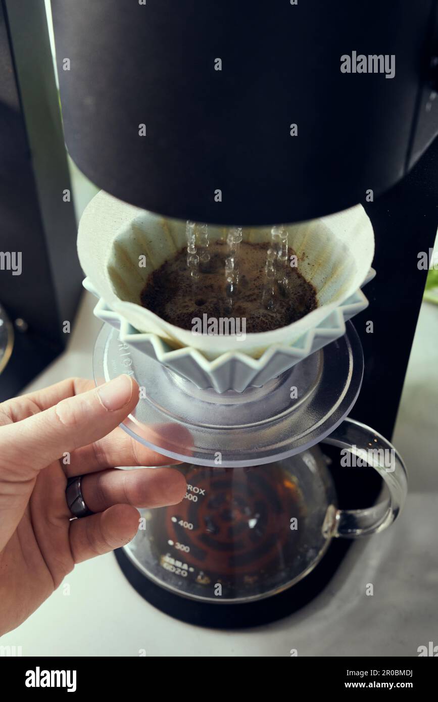 Versare sulla macchina l'acqua sul caffè macinato fresco. Foto Stock