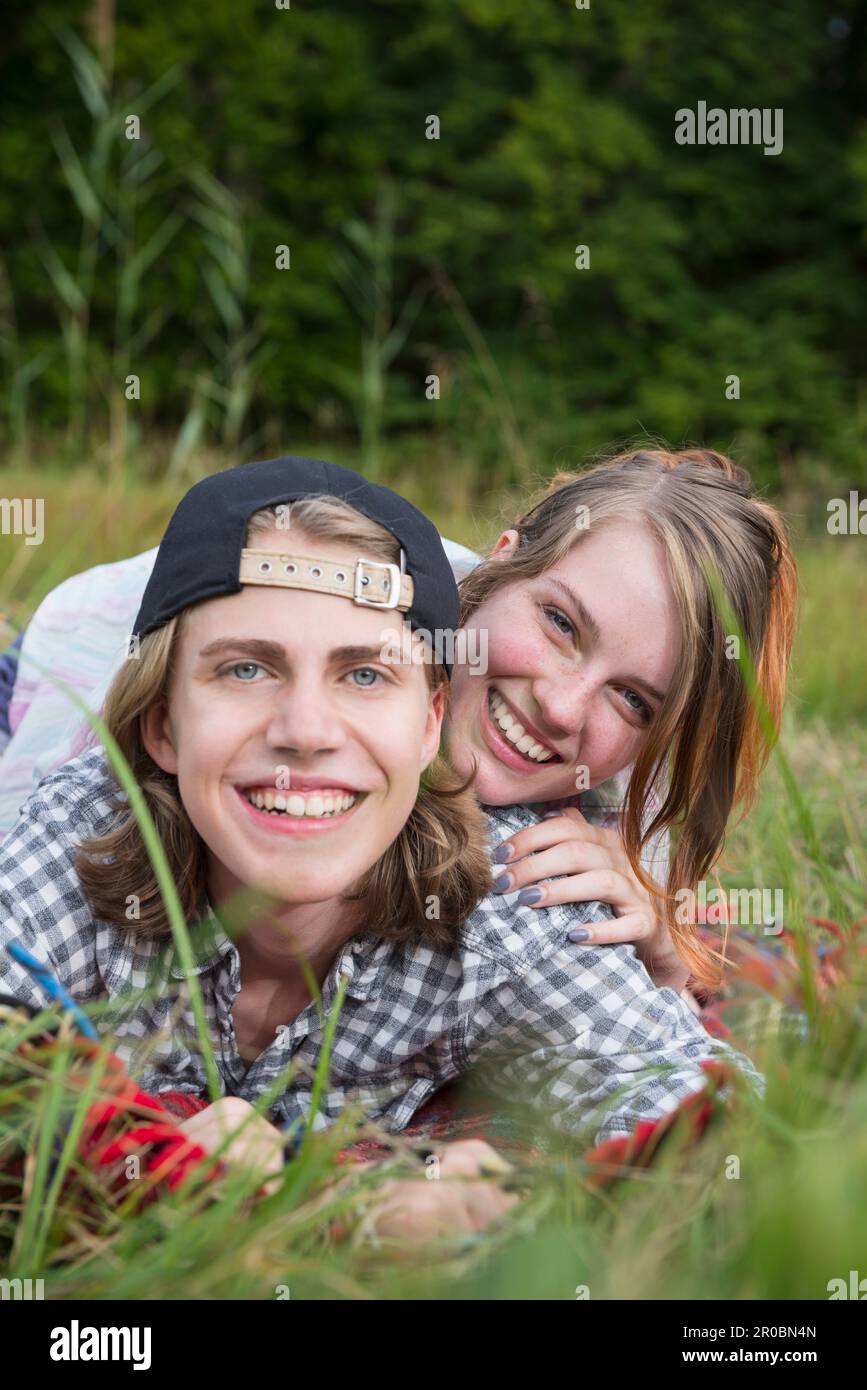 Ritratto di una giovane coppia sdraiata in prato e sorridente, Baviera, Germania Foto Stock