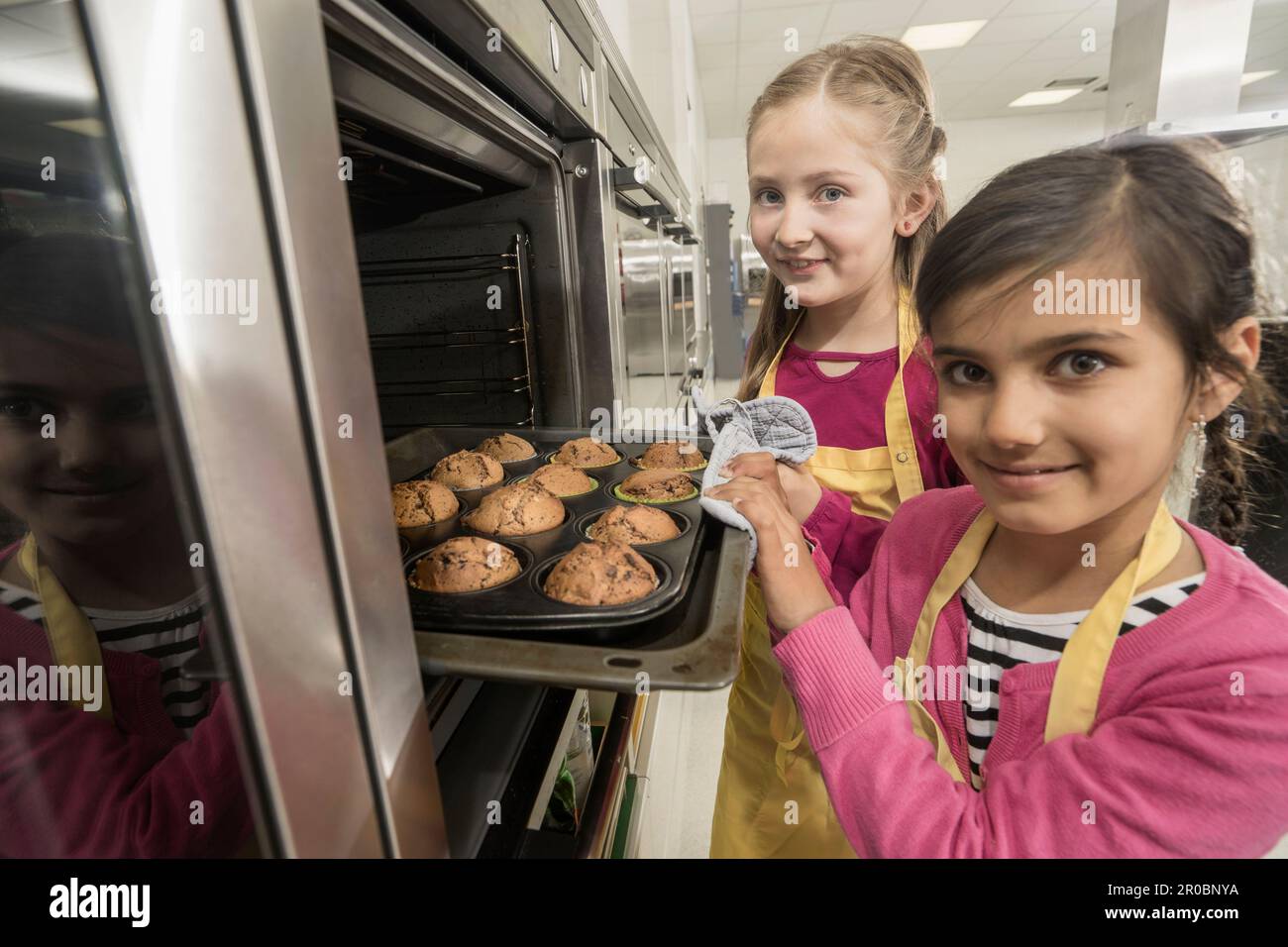 Studentesse che rimuovono i muffin dal forno in classe di economia domestica, Baviera, Germania Foto Stock