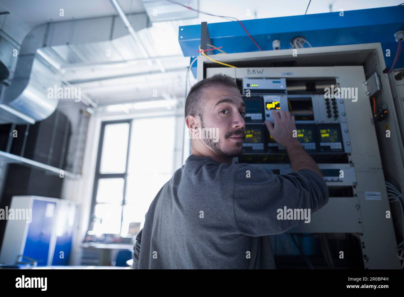 Ritratto di un giovane ingegnere maschio che controlla un gruppo di comando nella sala di controllo, Friburgo in Breisgau, Baden-WÃ¼rttemberg, Germania Foto Stock