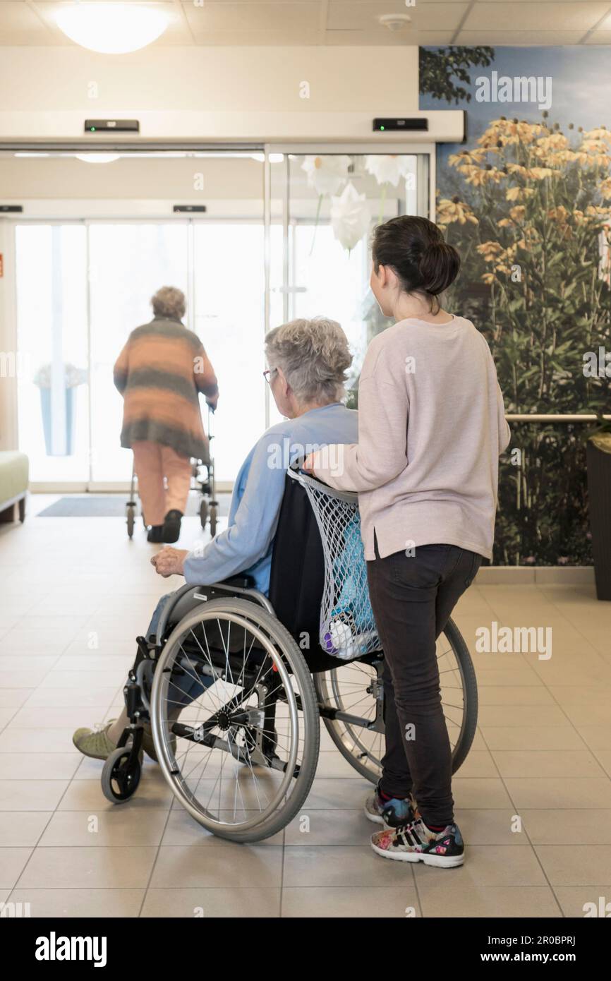 Donna anziana in sedia a rotelle con ragazza in casa di riposo Foto Stock