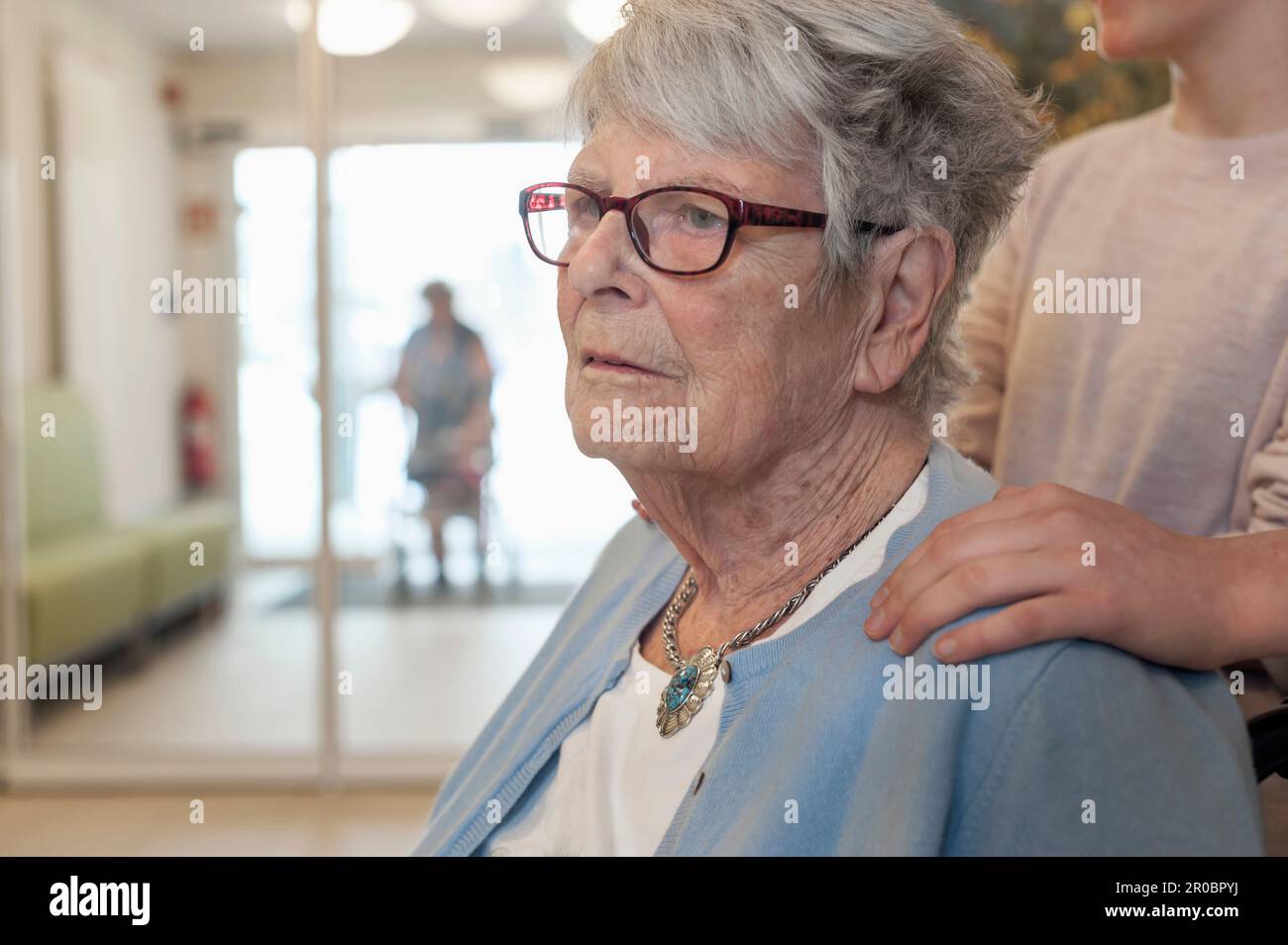 Donna anziana con mano sulla spalla del bambino grande in casa di riposo Foto Stock