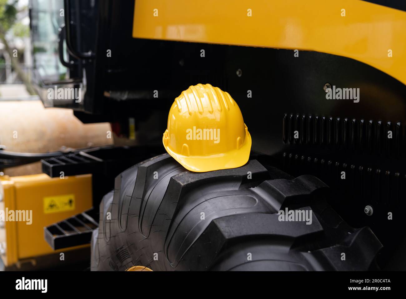 Un elmetto giallo si trova sulla ruota di una macchina da costruzione. Foto di alta qualità Foto Stock