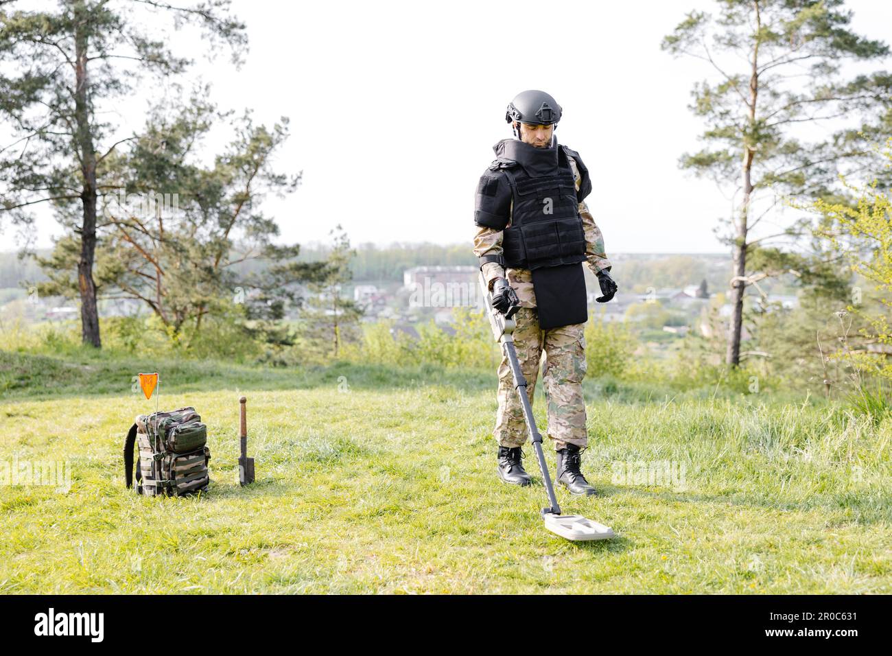 Un uomo in uniforme militare e giubbotto antiproiettile lavora nella  foresta con un metal detector. Un minatore esegue lavori di sminamento del  territorio Foto stock - Alamy