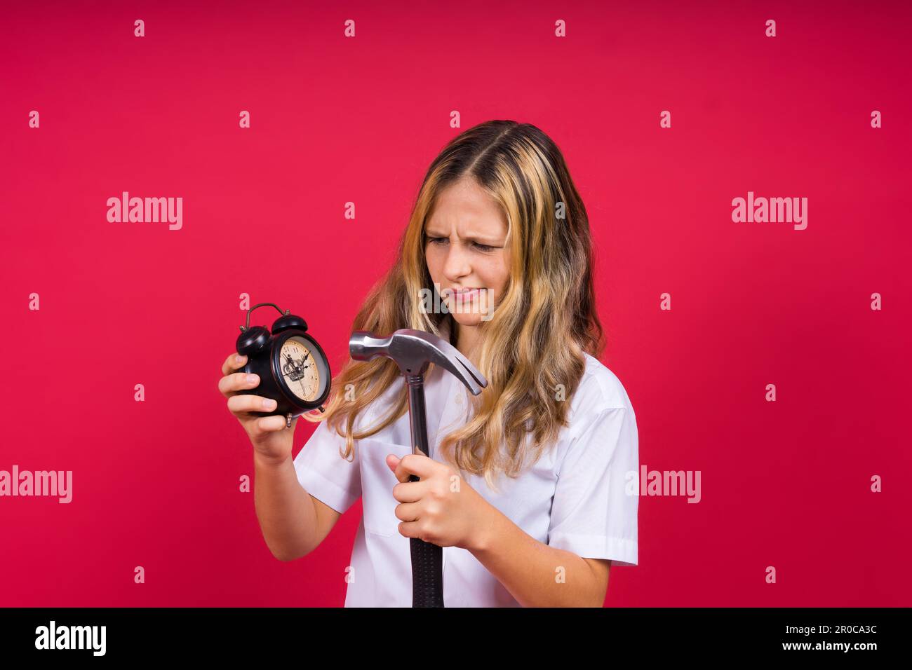 Ragazza bambino che tiene il martello e sveglia sorridente con sorriso felice e fresco sul viso. visualizzazione dei denti. Foto Stock