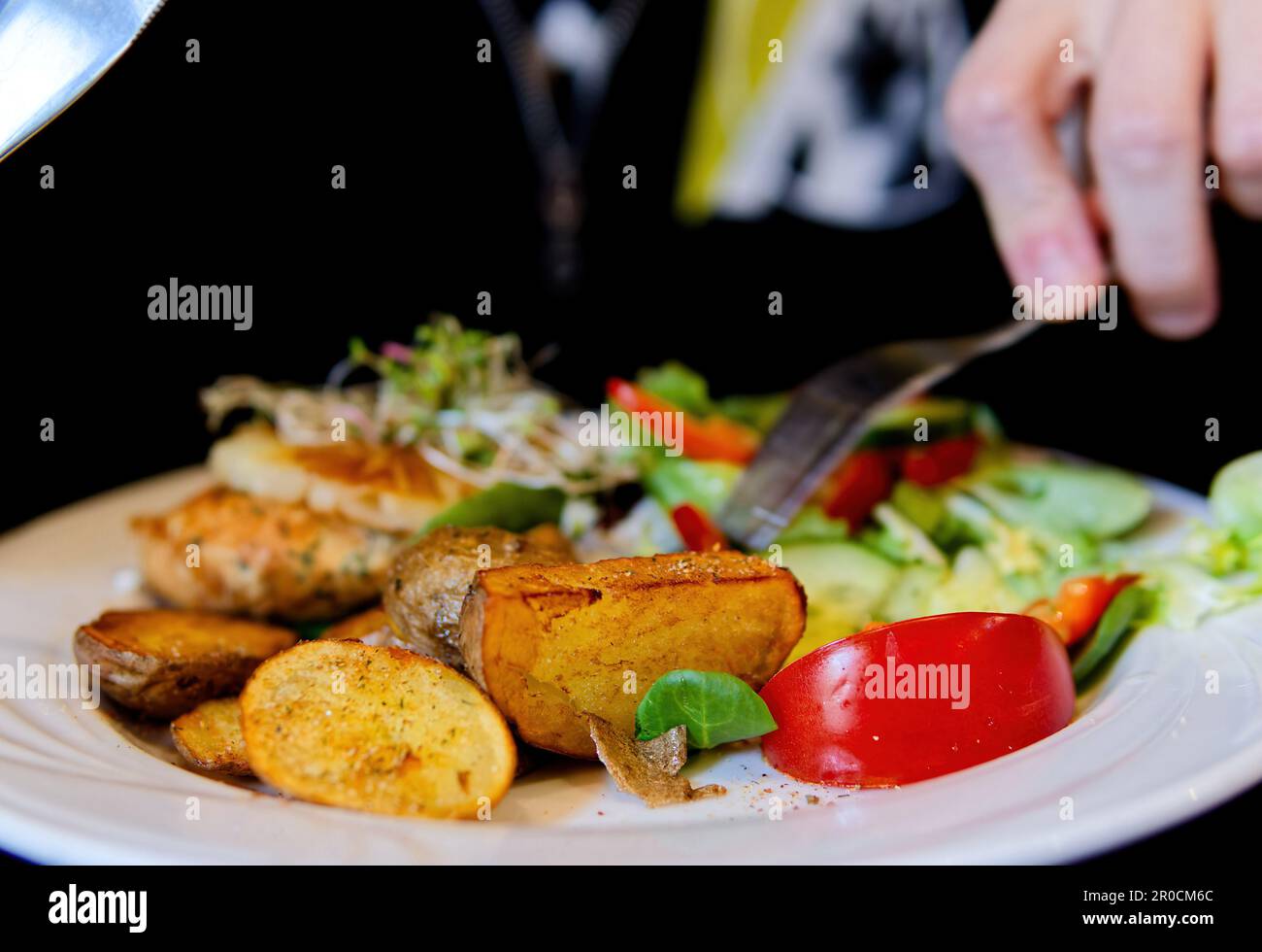 Un'immagine di una persona che tiene una forchetta, pronta a scavare in un piatto di cibo Foto Stock