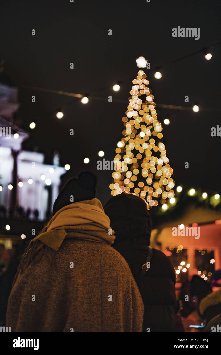 Due donne che camminano verso il grande albero di Natale godendo la stagione di festa Foto Stock