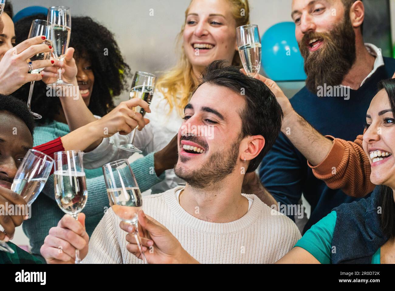 Un gruppo di amici felici allietando le bevande del vino bianco nel paese. Festa di compleanno di un ragazzo, brinda con vino frizzante con gli amici. Momento di risate e. Foto Stock