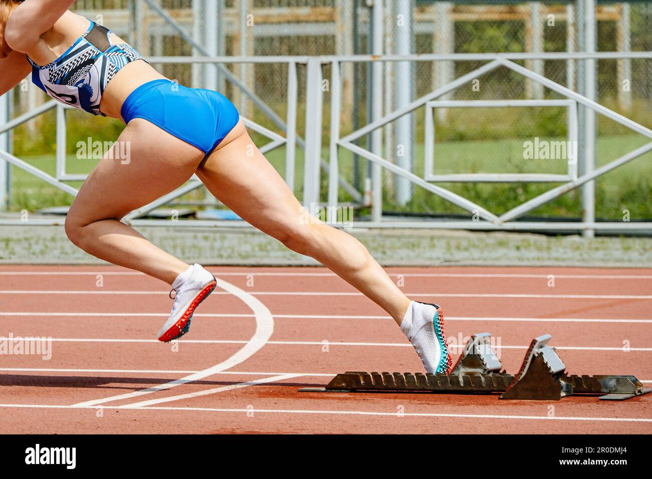 primo piano sprinter femminile inizia a correre dai blocchi di partenza nei campionati di atletica estivi Foto Stock