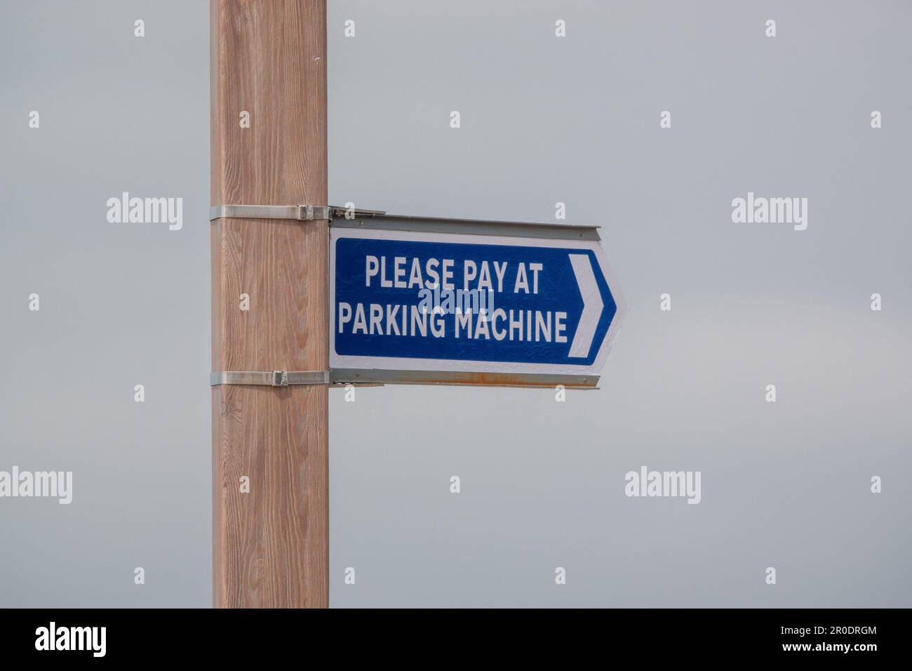 Un cartello per favore paga al parcheggio su un palo di legno presso un parcheggio auto Foto Stock