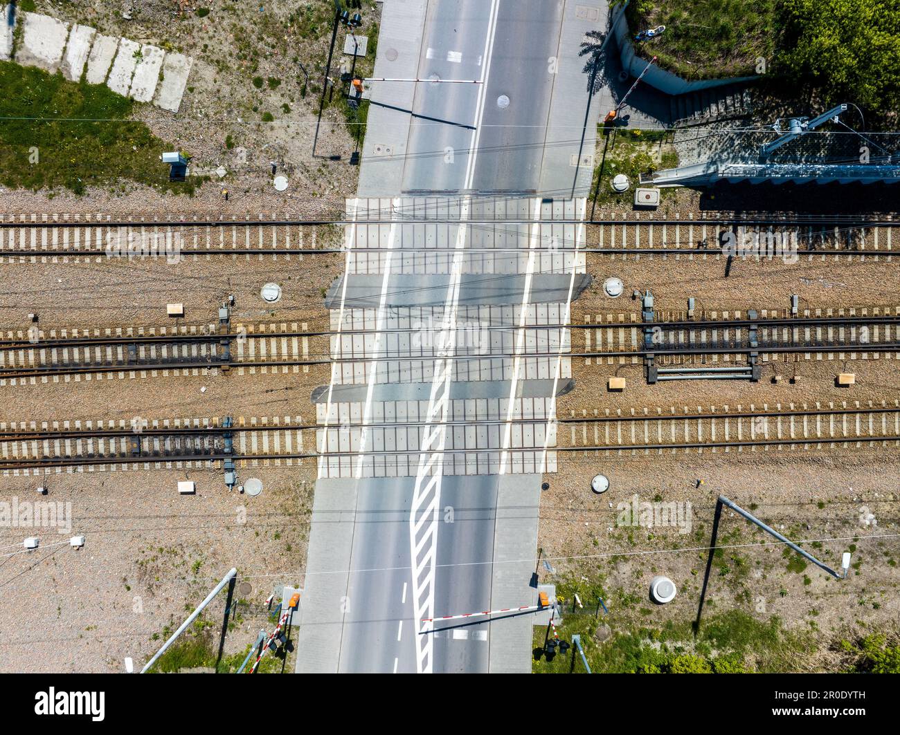 Attraversamento a livello ferroviario con barriere semichiuse. Binari ferroviari con fascette in cemento e pannelli di commutazione su ghiaia. Vista aerea dall'alto Foto Stock