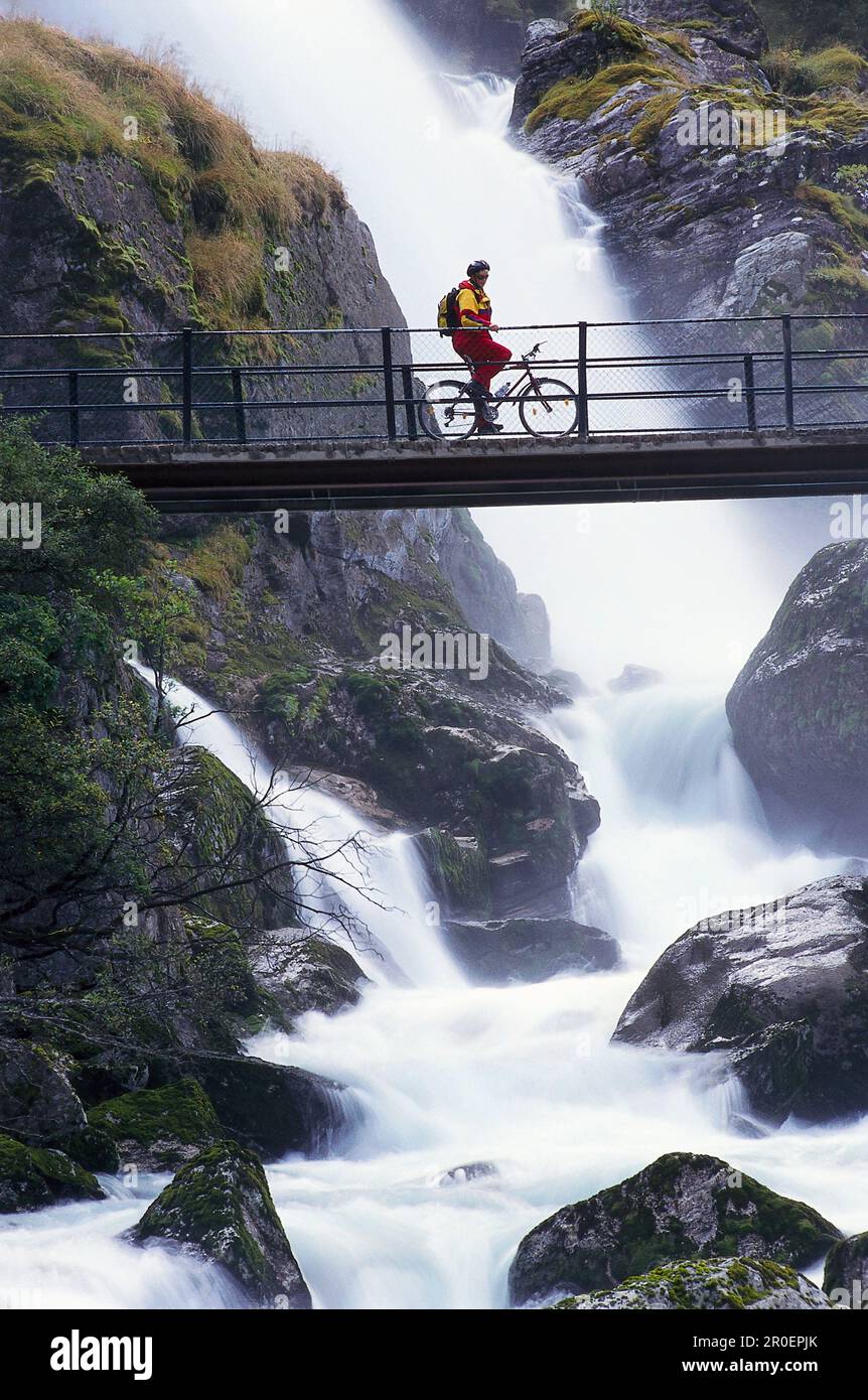 Mountain Biker presso la cascata Kleivafossen, ghiacciaio di Briksdal, Norvegia Foto Stock