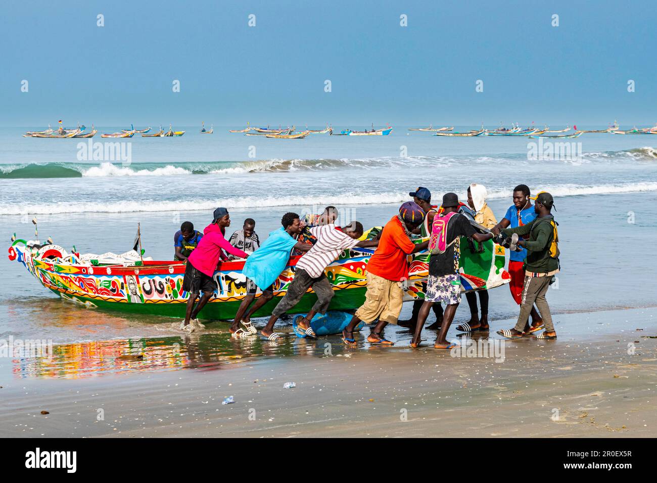 Uomini che tirano colorata barca da pesca, Cap Skirring, Casamance, Senegal Foto Stock