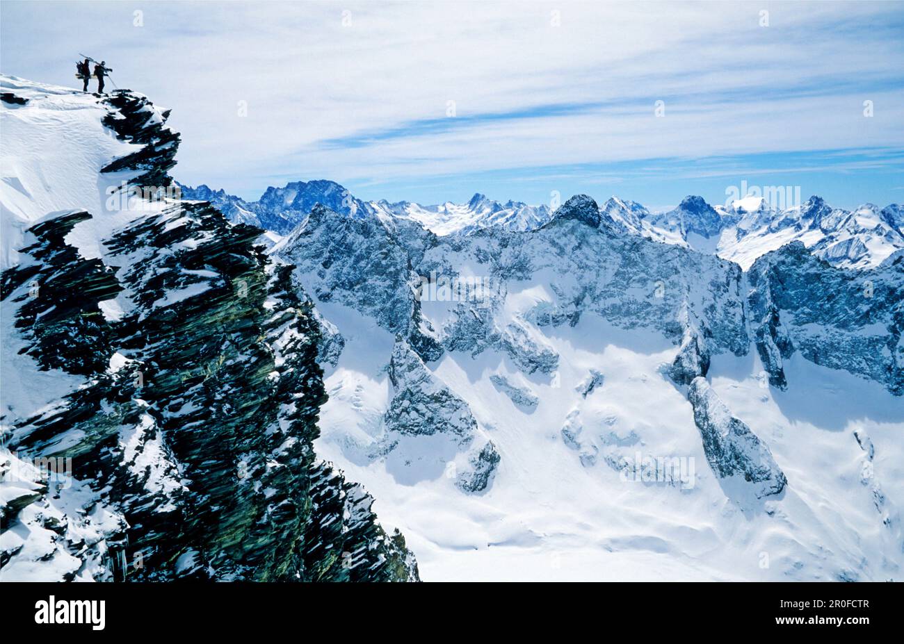 Freeriders in cima a una parete rocciosa, che si affaccia su un paesaggio montano remoto. Dome de la Lauze, la grave, Oisans, Parc National des Ecrins, Foto Stock