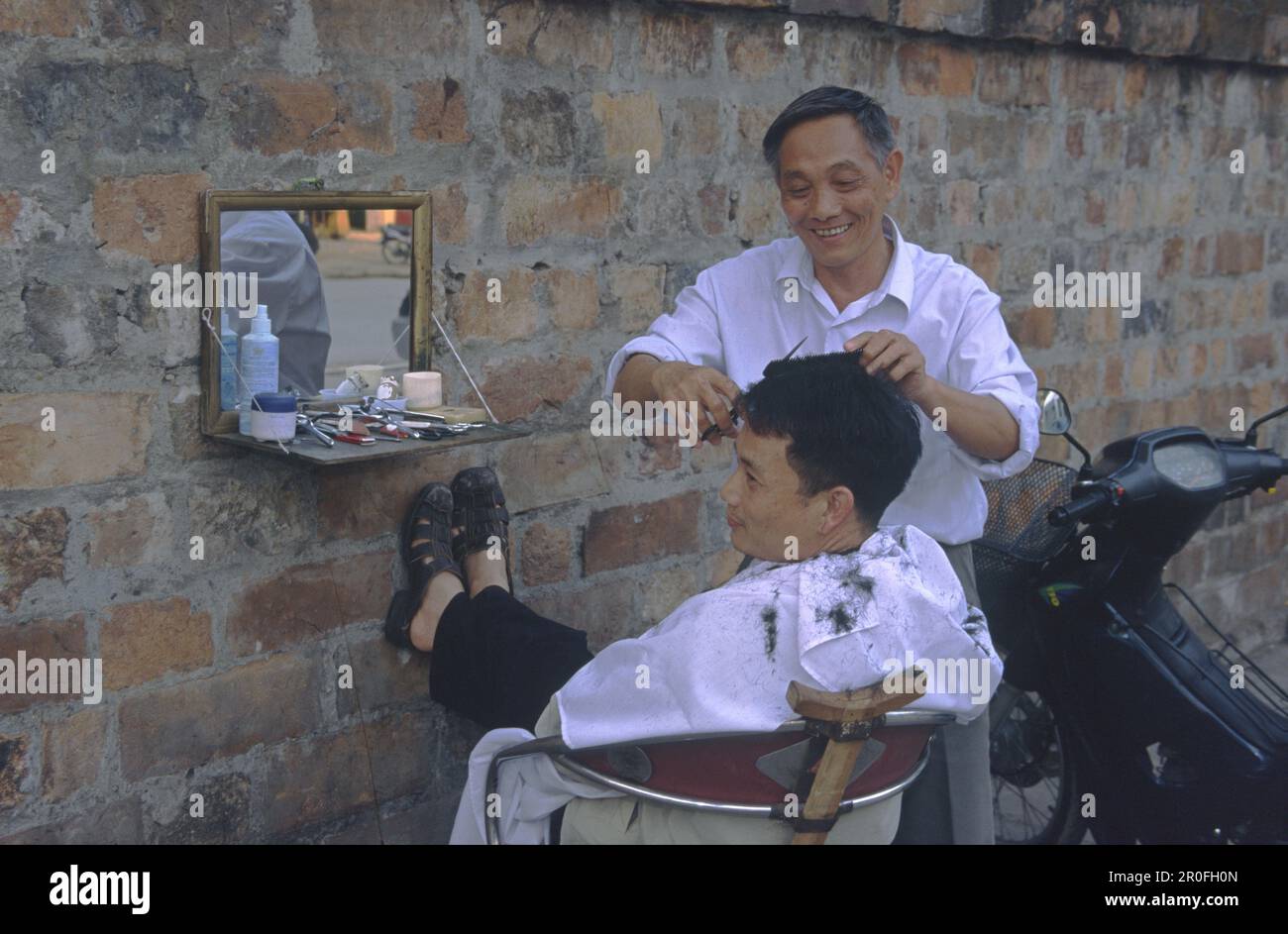 Parrucchiere con cliente, all'aperto, Hanoi, Vietnam Foto Stock