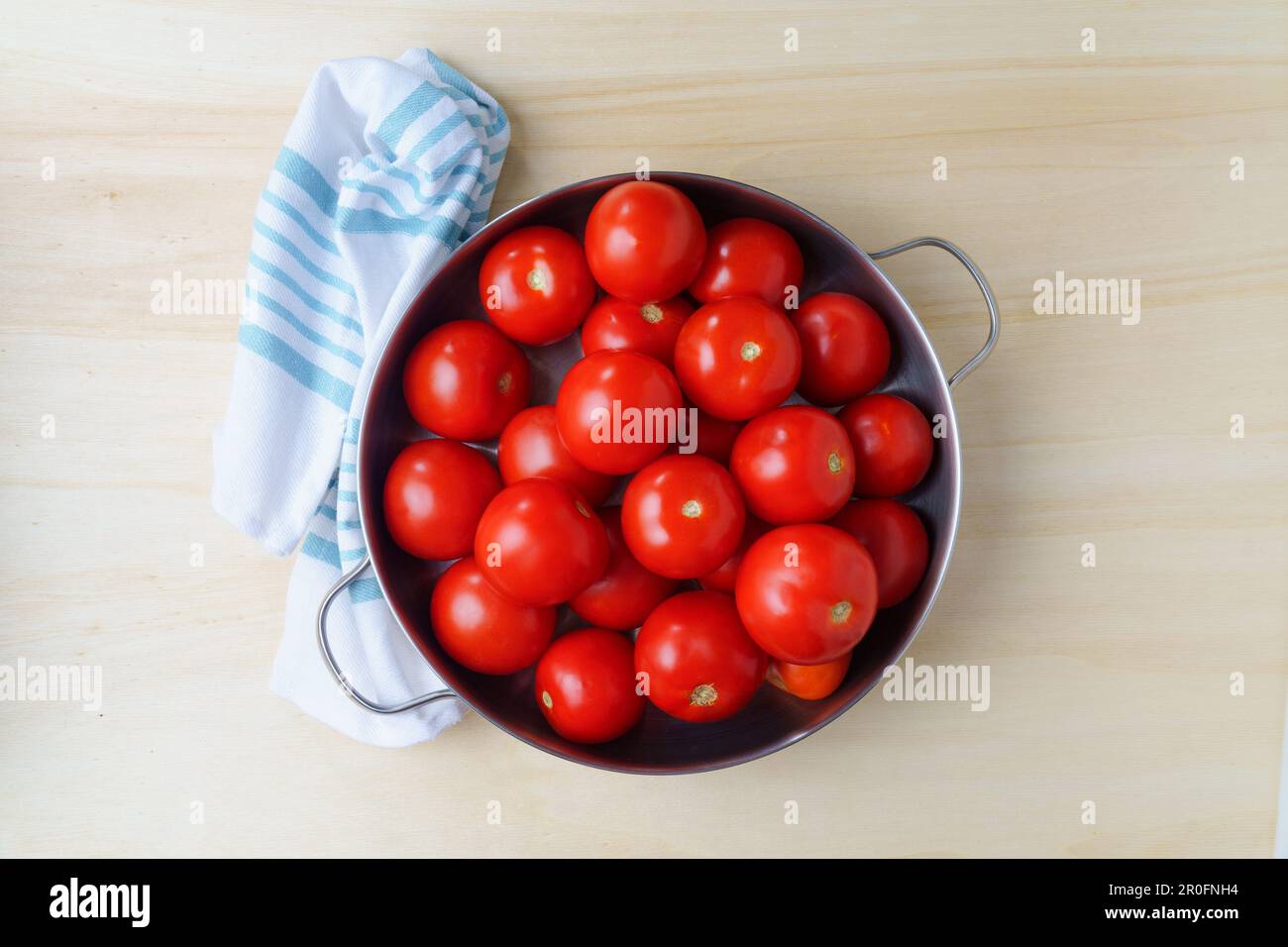 Pomodori freschi maturi in una ciotola di ferro su un tavolo di legno, primo piano Foto Stock