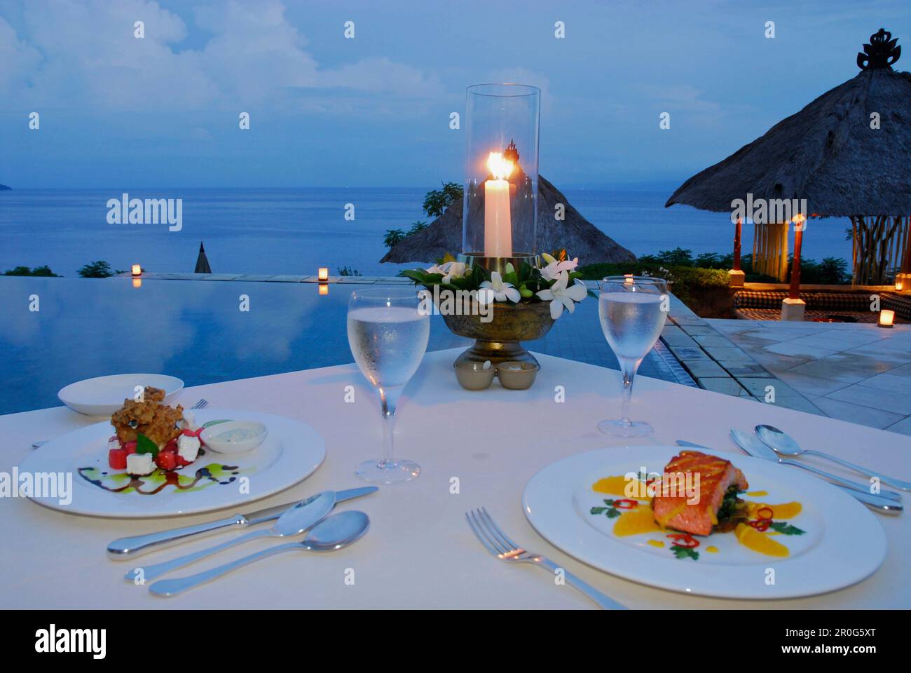 Un tavolo è posato presso la piscina al Amankila Resort in serata, Candi Dasa, Bali orientale, Indonesia, Asia Foto Stock
