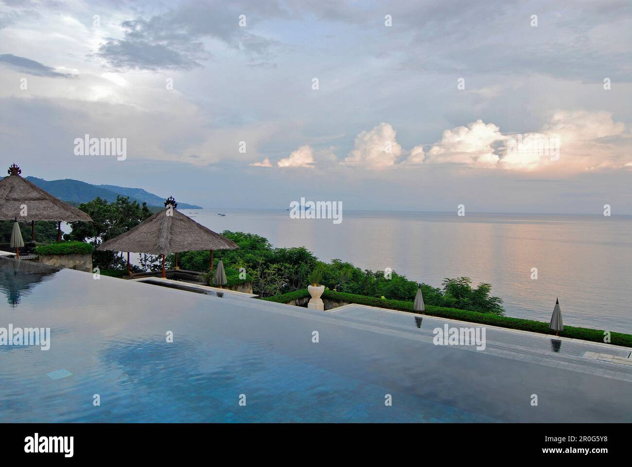 La piscina a sfioro deserta al Resort Amankila sotto il cielo nuvoloso, Candi Dasa, Bali orientale, Indonesia, Asia Foto Stock