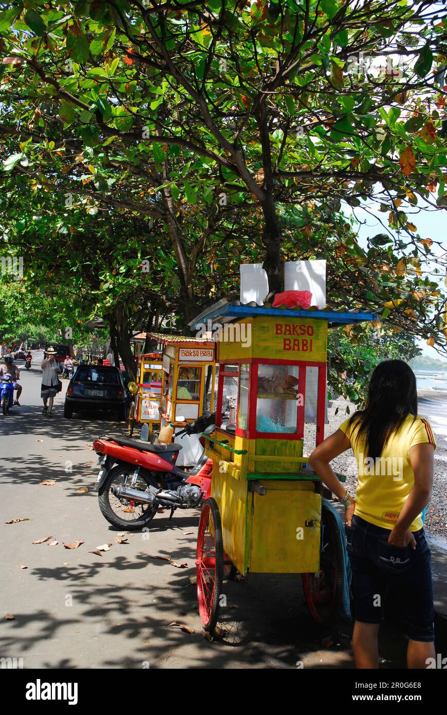 Una donna che si trova accanto a una bancarella di cibo sul lato della strada, Candi Dasa, Bali orientale, Indonesia, Asia Foto Stock