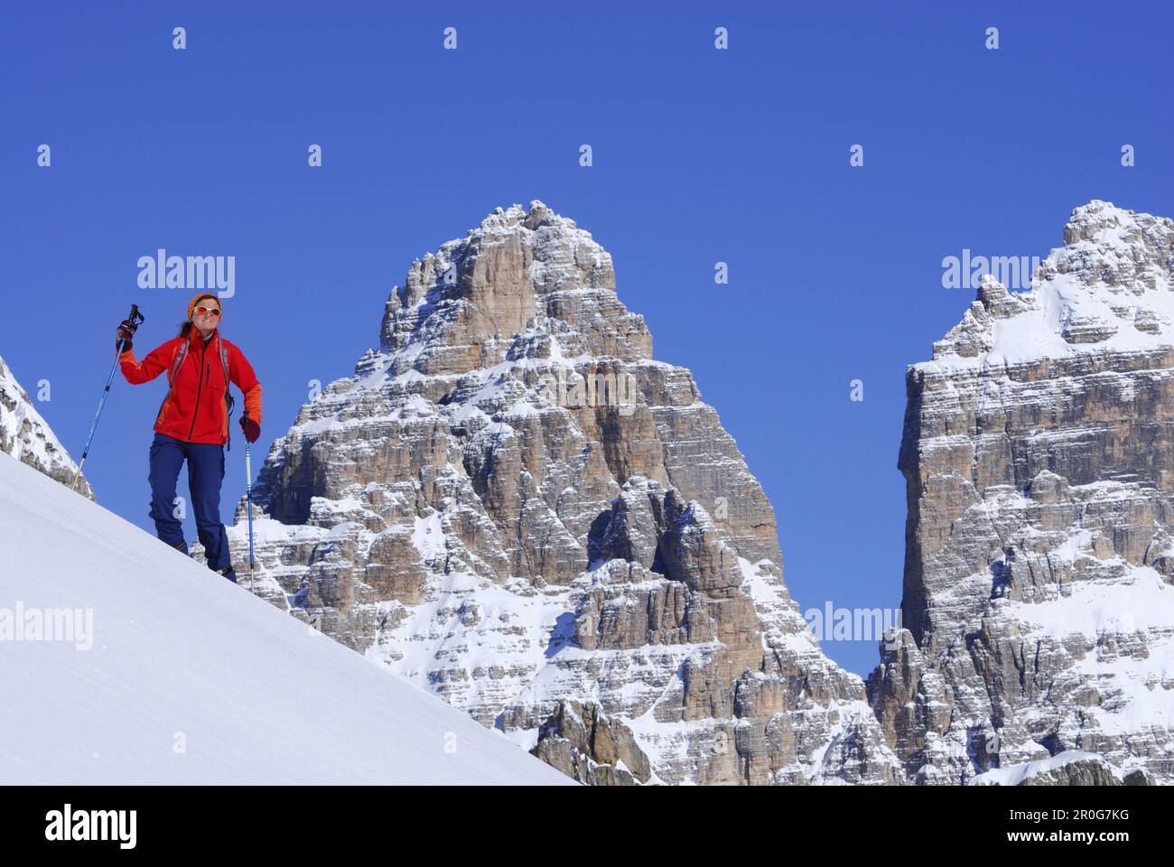 Donna backcountry ski, tre Cime di Lavaredo in background, Cadini range, Dolomiti, Trentino-Alto Adige/Südtirol, Italia Foto Stock