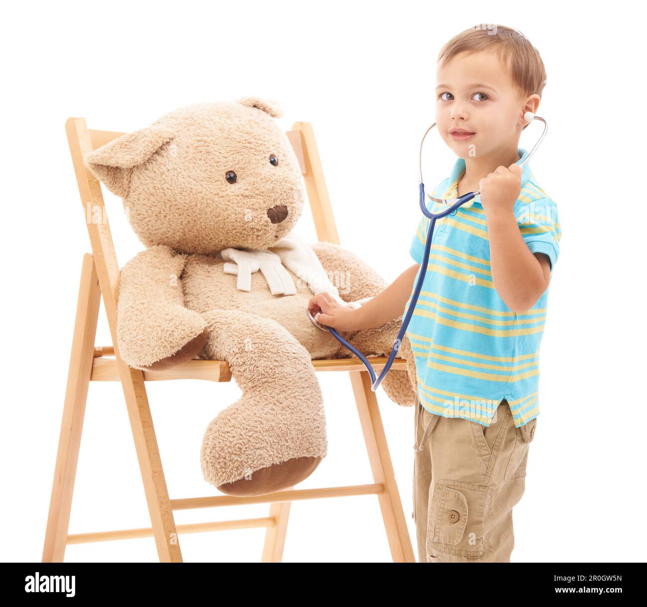 Medico di gioco. Foto studio di un giovane ragazzo che gioca con il suo orsacchiotto e uno stetoscopio. Foto Stock