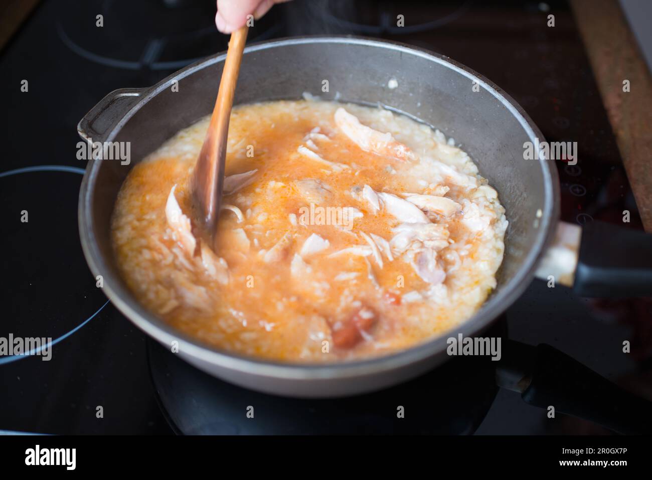 Primo piano di una donna anziana che cucinava riso con pollo a casa Foto Stock