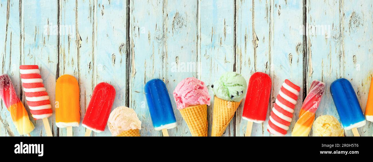 Varietà di coloratissime papicles estive e gelati. Vista dall'alto bordo inferiore su uno sfondo rustico di legno blu banner. Spazio di copia. Foto Stock