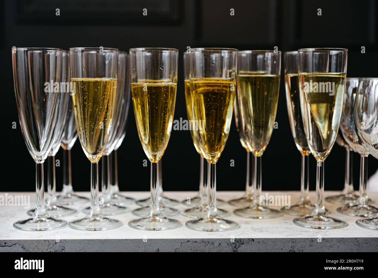Una fila di flute di champagne piene di spumante rinfrescante, per celebrare occasioni speciali. Un brindisi alla celebrazione: Bicchieri di vino in una fila. Foto Stock